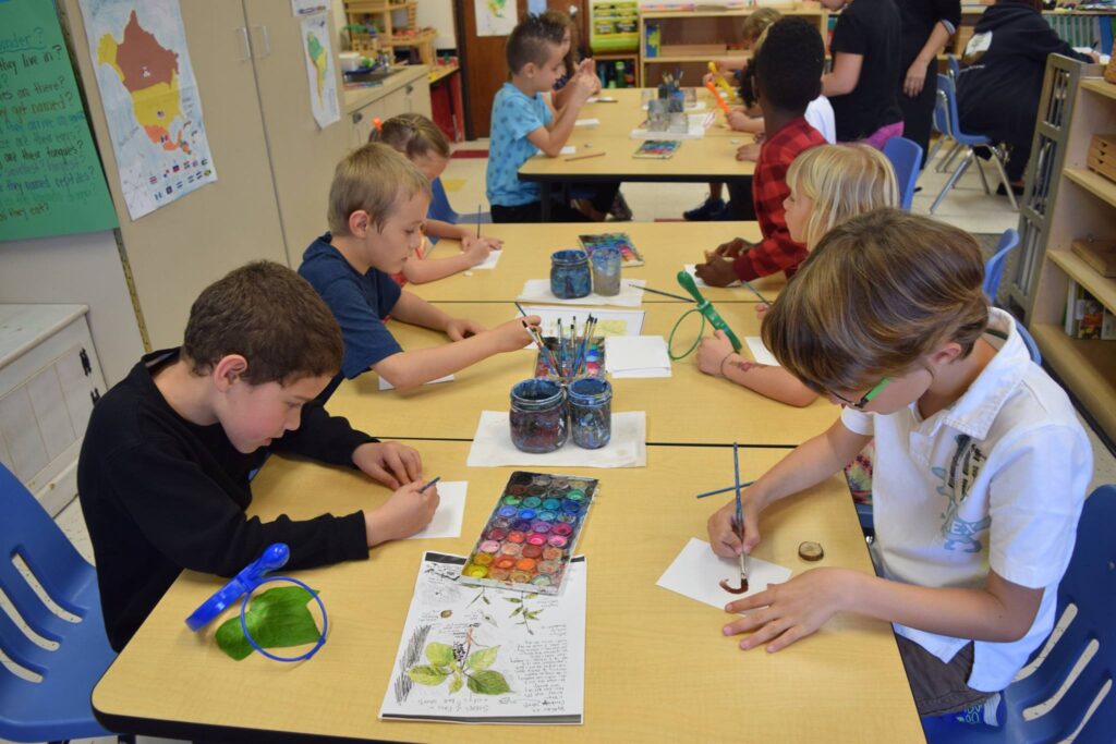 How to Teach Art to Different Ages and Interests in One Classroom, boys and girls in a classroom siting down painting and looking at nature.